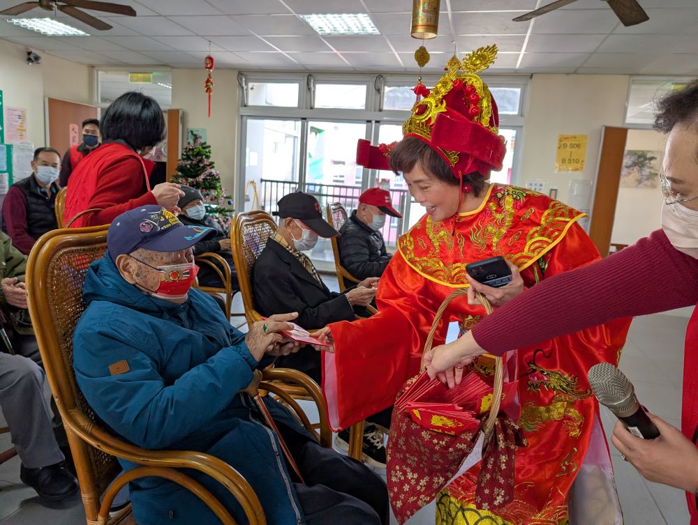 迎財神好運到 板橋榮家長輩喜上眉梢收開運金鈔 1 《圖說》板橋榮家主任陳桂美扮成女財神,將開運金鈔及糖果發送到長輩手中,讓大家都「吃甜甜好過年、拿金鈔賺大錢」。〈板橋榮家提供〉